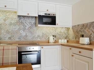 a kitchen with white cabinets and a stove top oven at The Byres Tan in St Bees