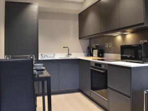 uma cozinha com armários a preto e branco e um lavatório em Riverview Apartment em Backbarrow