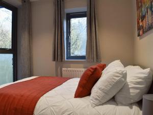 a bedroom with a bed with red and white pillows at Riverview Apartment in Backbarrow