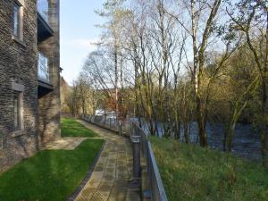 a walkway next to a river next to a building at Riverview Apartment in Backbarrow