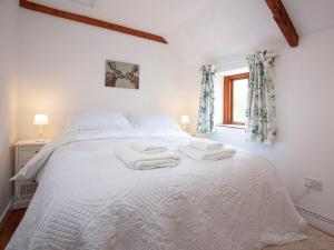 a bedroom with a white bed with towels on it at The Hayloft - Uk32686 in Sheepstor