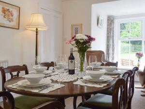 una mesa con una botella de vino y un jarrón de flores en Tarn House, en Wooler