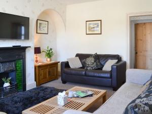 a living room with a leather couch and a fireplace at Lyndale House in Pateley Bridge