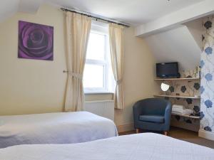 a bedroom with a bed and a chair and a window at Lyndale House in Pateley Bridge