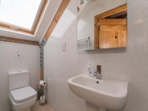 een badkamer met een wastafel, een toilet en een raam bij Y Beudy in Efenechtyd