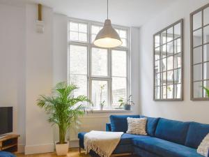 a living room with a blue couch and windows at Old Parish Hall in Ramsgate