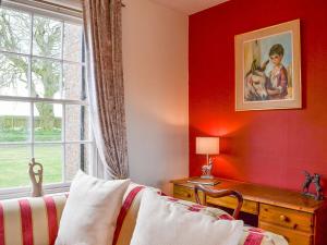 una camera da letto con una parete rossa e una finestra di Highbury Farm Cottage a Wharram le Street