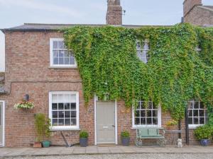 una casa di mattoni ricoperta di edera con una porta bianca di Highbury Farm Cottage a Wharram le Street