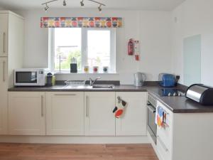 uma cozinha com armários brancos, um lavatório e uma janela em High Brow em Bowness-on-Windermere