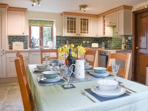 a kitchen with a table with plates and wine glasses at Primrose Bank in Tirril