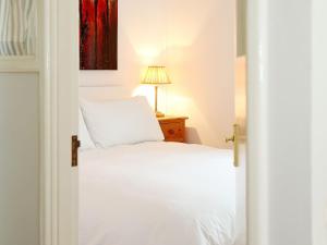sypialnia z białym łóżkiem i lampką w obiekcie Garden Cottage w mieście Icklesham