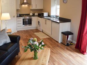eine Küche und ein Wohnzimmer mit einer Vase aus Blumen auf dem Tisch in der Unterkunft Faodail-uk34218 in Aberfoyle