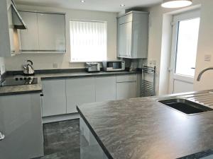 cocina con armarios blancos y encimera de granito en Forest Walk en Coleford