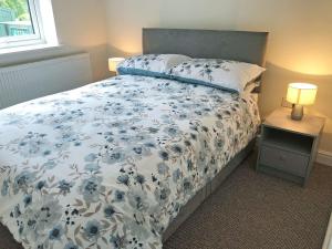 a bedroom with a bed with a blue and white comforter at Forest Walk in Coleford