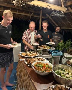 a group of men standing around a buffet of food at My Hostel Boracay in Boracay