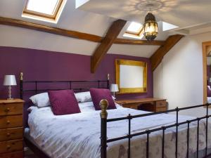 a bedroom with a large bed with purple walls at Pineview Cottage in Downderry