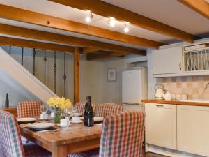 a kitchen with a wooden table with chairs and a kitchen at Pineview Cottage in Downderry