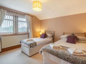 a bedroom with two beds and a window at Highfield Cottage in Hambleton