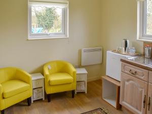 a kitchen with two yellow chairs and a table at Shepherds Hut 1 At Laddingford - Uk32531 in Yalding