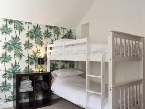 a bedroom with two bunk beds with palm trees wallpaper at Atlantic View in Westward Ho