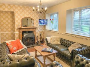 a living room with leather couches and a fireplace at New Cottage in Penmaenpool