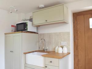 a kitchen with a sink and a microwave at Pepperpot Lodge in Baschurch