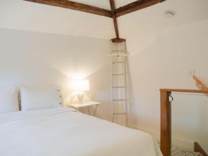 1 dormitorio con 1 cama blanca y 1 lámpara en Pepperpot Lodge, en Baschurch