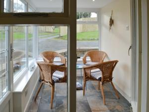 two chairs and a table in a room with windows at Dunstanburgh View in Craster