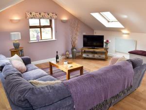 a living room with a large couch and a tv at Owls Rest in Burley in Wharfedale