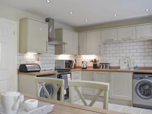 a kitchen with white cabinets and white appliances at Bank Side in Leyburn