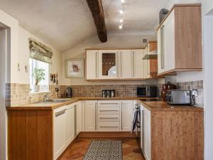 a kitchen with white cabinets and a sink at Beck Cottage in Mildenhall