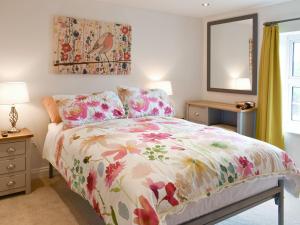 a bedroom with a bed with a floral comforter at Beck Cottage in Mildenhall