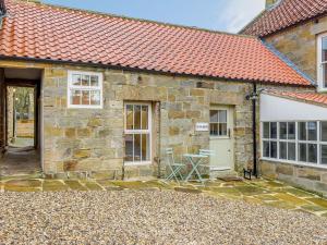 a stone house with a red roof and a courtyard at The Nook - Uk36720 in Glaisdale