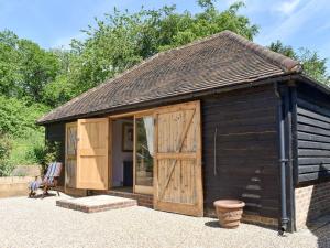 a large black shed with a wooden door at The Granary in West Hoathley