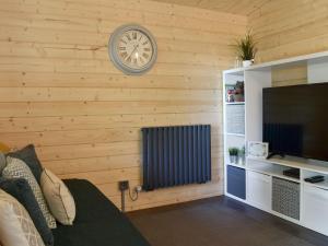 a living room with a television and a clock on the wall at Poppy Lodge in Minster