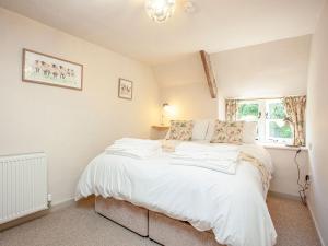 a bedroom with a bed with white sheets and a window at Splash Cottage in Widecombe in the Moor