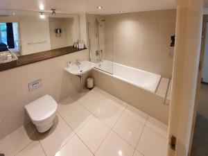 a bathroom with a toilet and a tub and a sink at Apartment 4, Zinc in Newquay