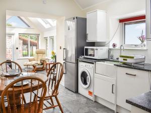 a kitchen with white appliances and a table and chairs at The Bothy in Kirktown of Auchterless