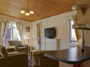 a living room with a tv and a couch and chairs at Lodge C- Uk33089 in Dinnet