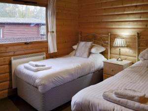 a bedroom with two beds in a log cabin at Holme Garth Lodge in Legbourne