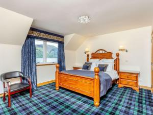 una camera con letto in legno e sedia di Lochside House - S4532 a Letterfearn