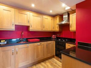 a kitchen with wooden cabinets and a red wall at Lower Deck in Dartmouth