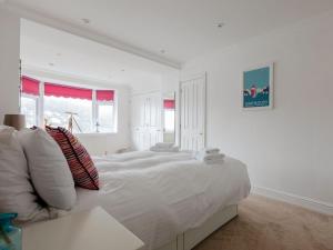 a white bedroom with a large white bed with pillows at Lower Deck in Dartmouth