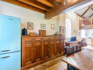 uma cozinha com armários de madeira, uma mesa e um frigorífico em St Andrews Church em East Barkwith