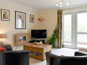 a living room with a flat screen tv and a table at Elizabeth House in Bampton