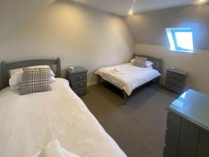 um quarto com duas camas e duas mesas de cabeceira em Puffin - Dubh Segir em Lerags