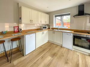 a kitchen with white cabinets and a wooden floor at The Firs - Uk33999 in Child Okeford