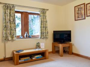 a living room with a television and a table and a window at Quarry Cottage in Highpeak Junction
