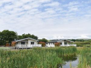 uma fila de casas rústicas ao lado de uma massa de água em Pine Lodge - Uk30007 em Lindal in Furness