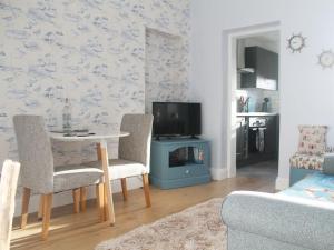 a living room with a table and chairs and a tv at Linne Foirthe in Dysart